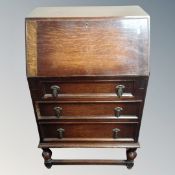 A 1930s oak writing bureau fitted with three drawers.
