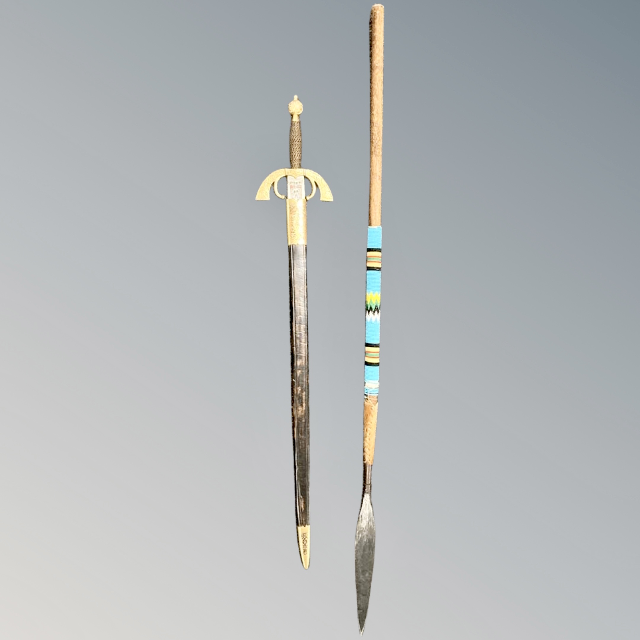 A reproduction ceremonial sword together with an African spear.