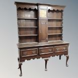 A 19th century oak Welsh dresser, fitted with central clock with pendulum and weights.