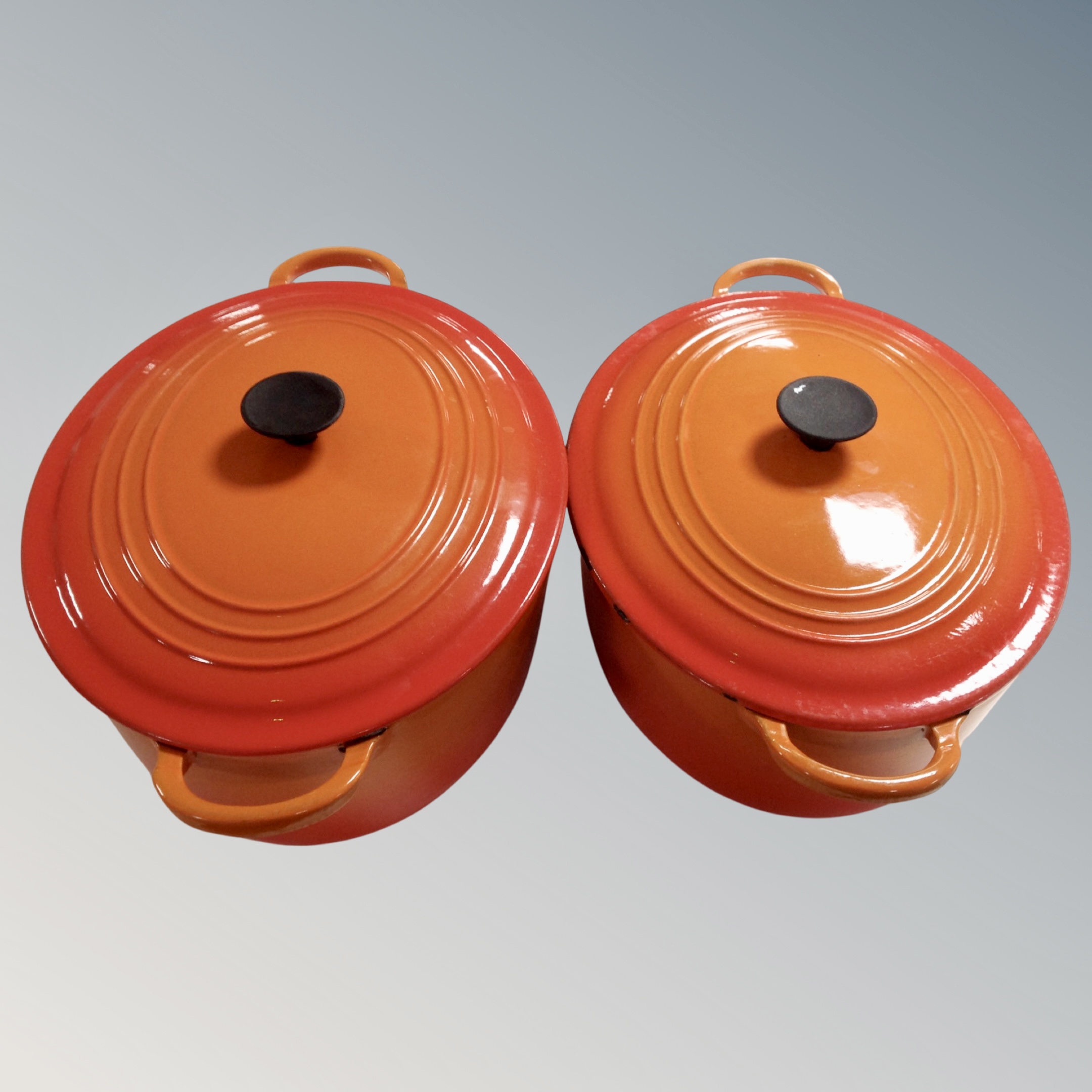 Two Le Creuset cast iron lidded casserole pans.