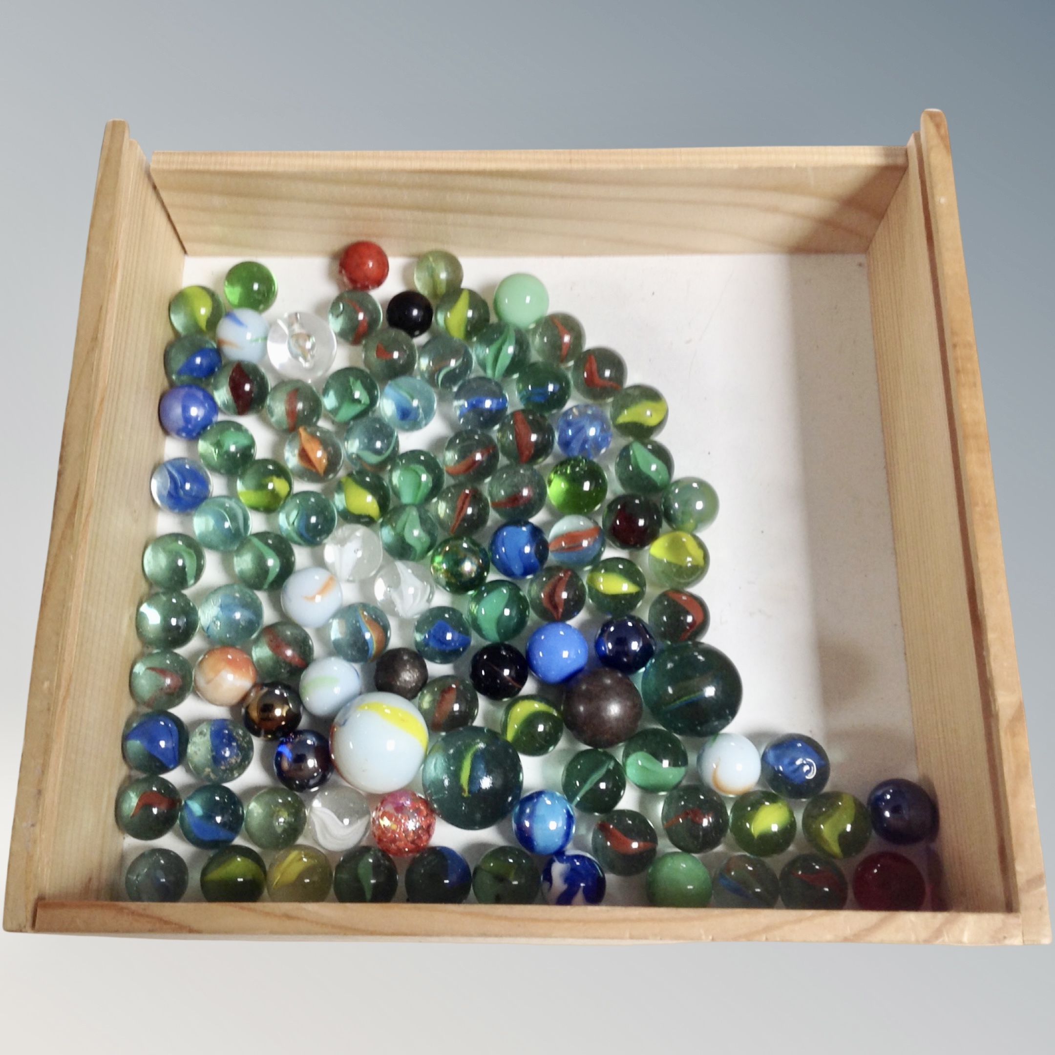 A pine drawer containing a quantity of glass marbles.