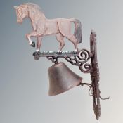 A cast iron bell on horse wall bracket.