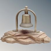 A vintage brass bell on an oak stand.