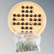 A wooden solitaire board with wooden marbles together with further bag of glass marbles