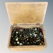 A wooden crate containing a large quantity of glass ceramic and metal marbles