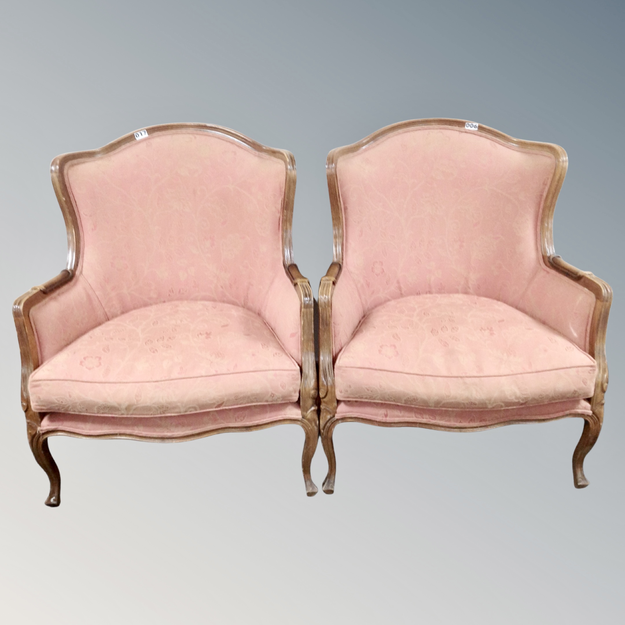 A pair of French style beech framed armchairs upholstered in salmon fabric