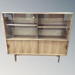 A mid century sliding glass door bookcase on raised legs