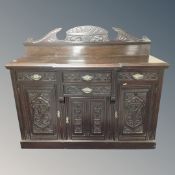 A Victorian break fronted carved triple door sideboard fitted with four drawers