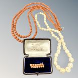 A two-strand coral necklace on yellow metal clasp, together with a coral brooch and a bone necklace.