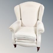 A Victorian style wingback armchair in cream fabric