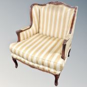 A French style carved beech armchair in golden and cream striped fabric