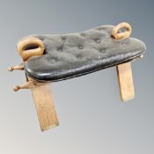 A middle eastern camel stool with leather saddle