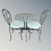 A cast aluminium patio table and two chairs