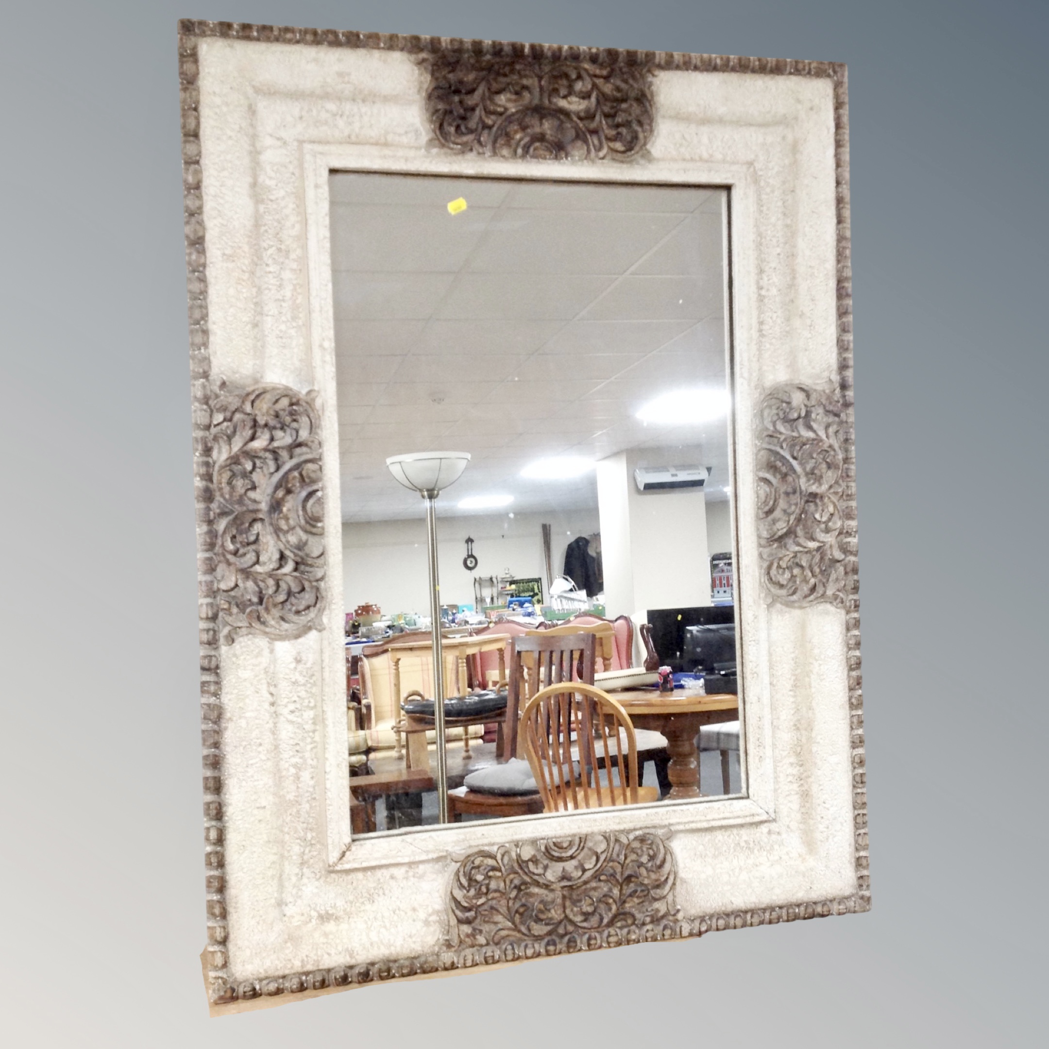 A contemporary over mantel mirror in faux stone effect frame