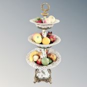 A decorative brass and ceramic three tier table centrepiece comport containing artificial fruit