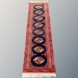 An Afghan runner, with a column of eight guls on indigo field within madder borders,