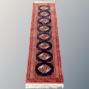 An Afghan runner, with a column of eight guls on indigo field within madder borders,