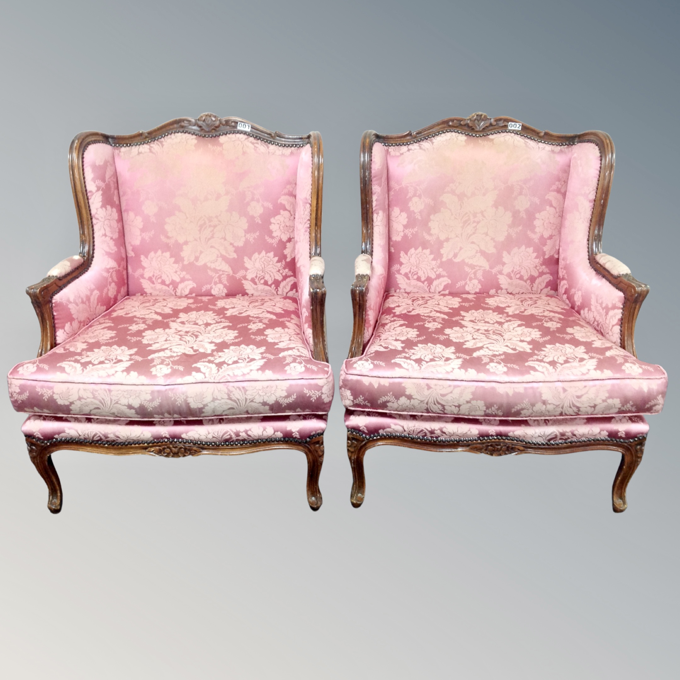 A pair of French style carved beech armchairs in pink floral fabric