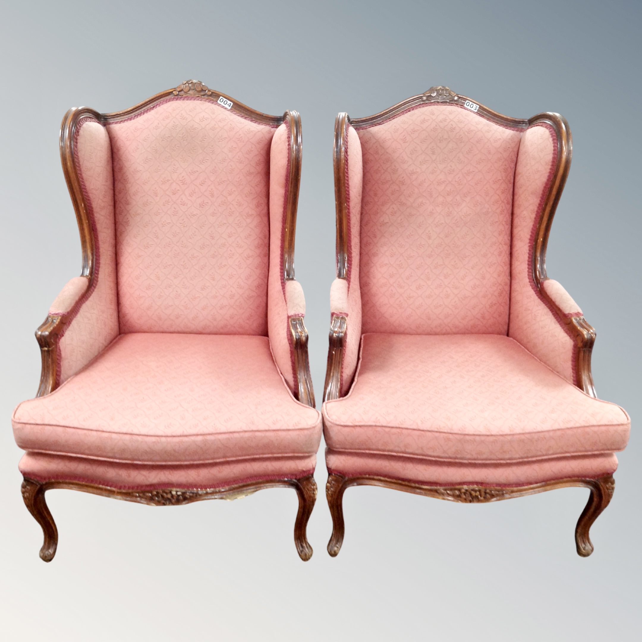 A pair of French style carved beech framed wingback armchairs in salmon fabric
