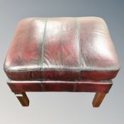 A leather upholstered footstool on raised legs