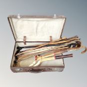 A vintage luggage case containing walking sticks and tennis rackets
