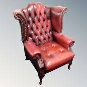 A Chesterfield oxblood leather wingback armchair with non-matching cushion (a/f)