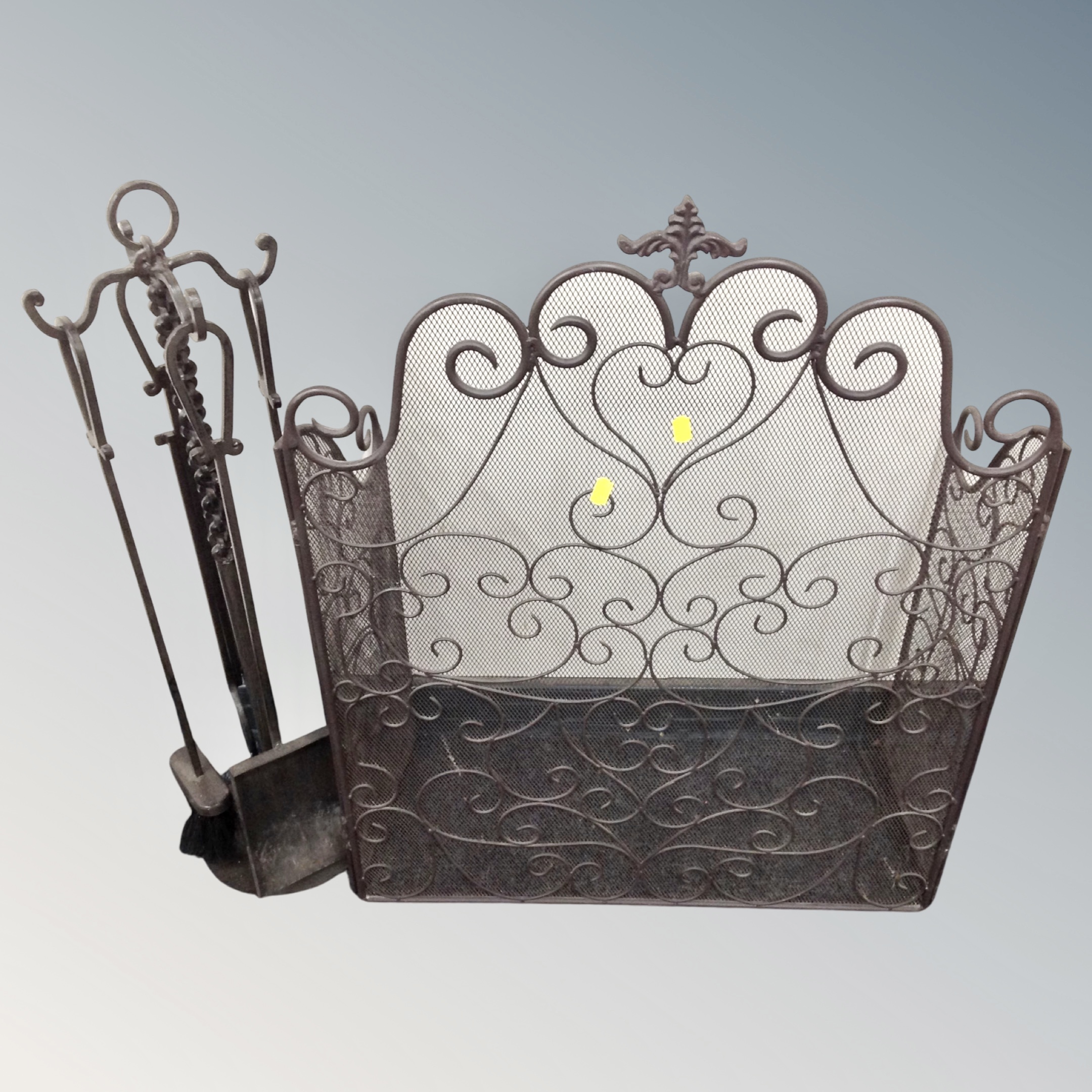 A wrought iron three way folding spark guard together with a similar four piece companion set on