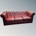 A Chesterfield oxblood leather three seater settee and armchair with non-matching cushion (2)