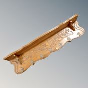 A contemporary oak carved wall shelf with seven metal hooks,