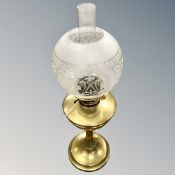 An antique brass oil lamp with glass shade and chimney