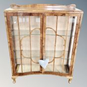 A 1930s shaped walnut double door display cabinet.