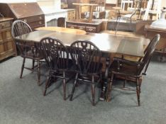 An oak refectory pull-out dining table together with a set of four Windsor chairs,