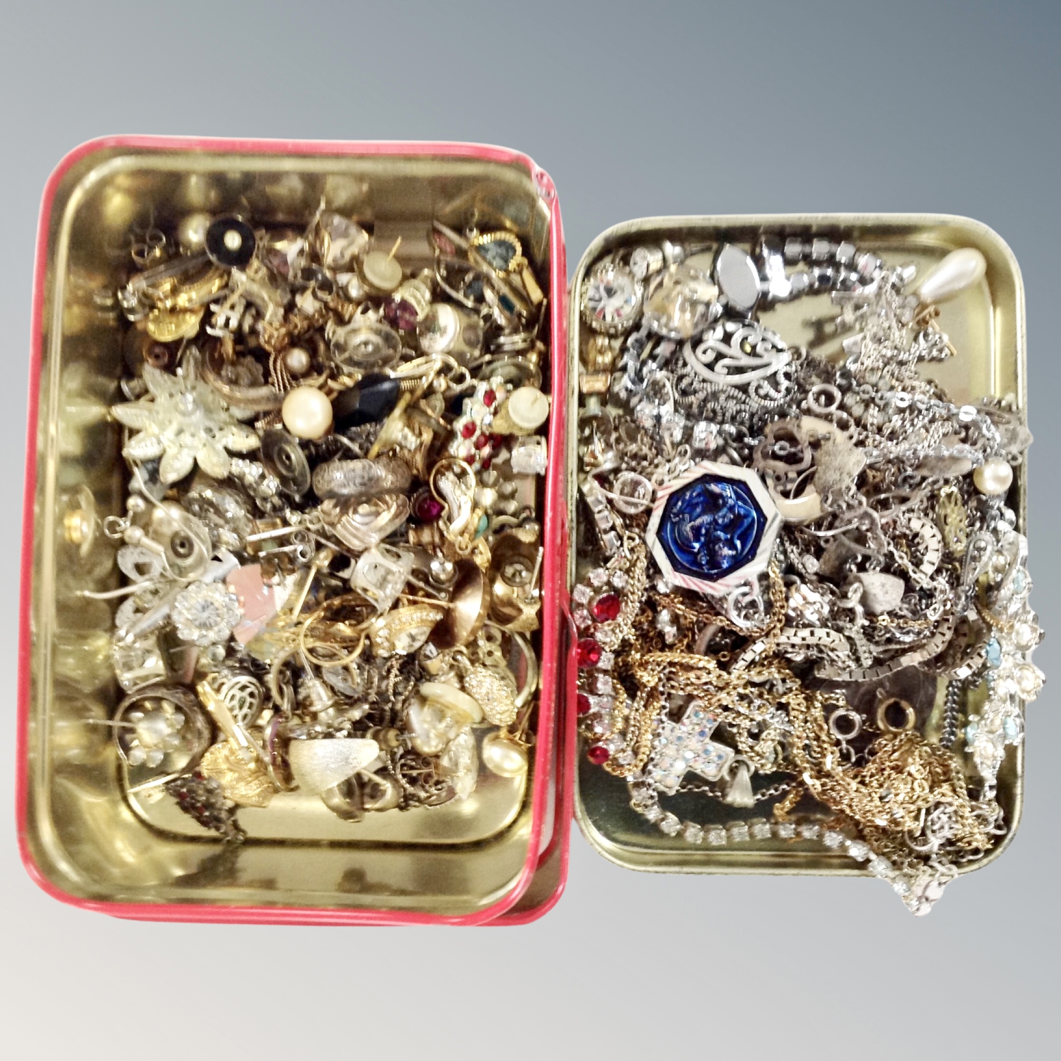 A tin containing a quantity of costume jewellery including gilt and silver finish chains, earrings,