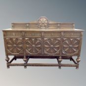 A 19th century oak four door sideboard fitted with four drawers with lion mask handles