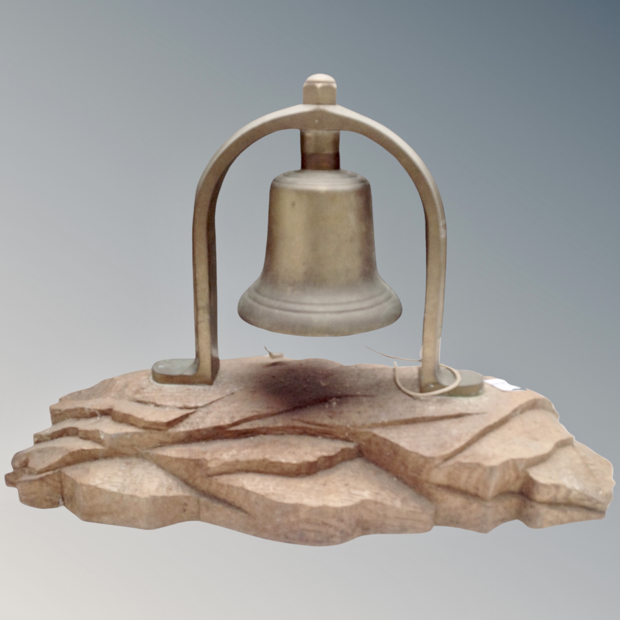 A vintage brass bell on an oak stand.