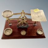 A set of antique brass postal scales and weights mounted on a board.