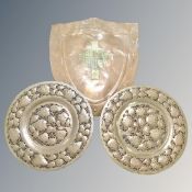 A pair of copper pierced and beaten floral wall plaques and copper shield with brass crest