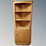 An Ercol elm and beech Windsor open corner unit fitted with cupboard below