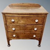 A 20th century oak three drawer chest with glass handles.