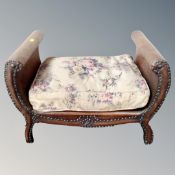 An early 20th century footstool upholstered in brown studded leather.