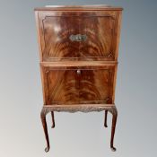 A 20th century mahogany double door cocktail cabinet fitted with fall front music cabinet below on