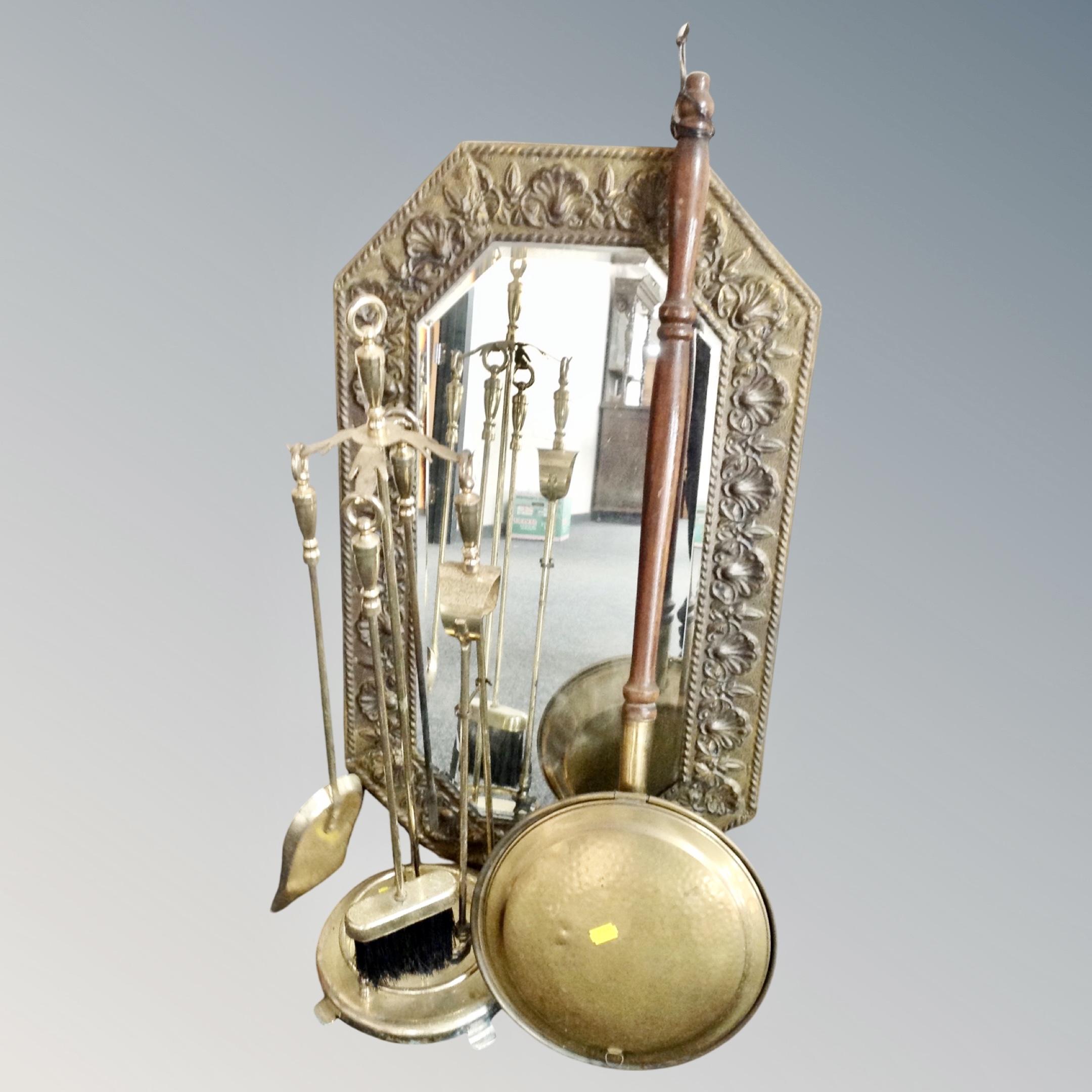 An octagonal brass framed embossed bevel edged mirror together with a four piece companion set on