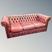 An Oxblood Chesterfield three seater club settee and armchair (odd cushions)