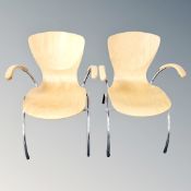 A pair of contemporary plywood dining chairs on tubular metal legs.