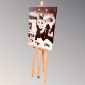 A wall canvas of Audrey Hepburn together with an artist's easel.