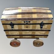 A metal and wooden bound trunk on metal wheels