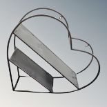 A contemporary metal heart shaped two tier wall shelf