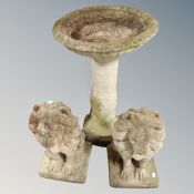 A concrete bird bath together with a pair of figures of lions