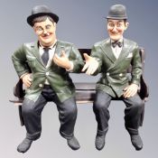 A composite figure of Laurel and Hardy seated on bench