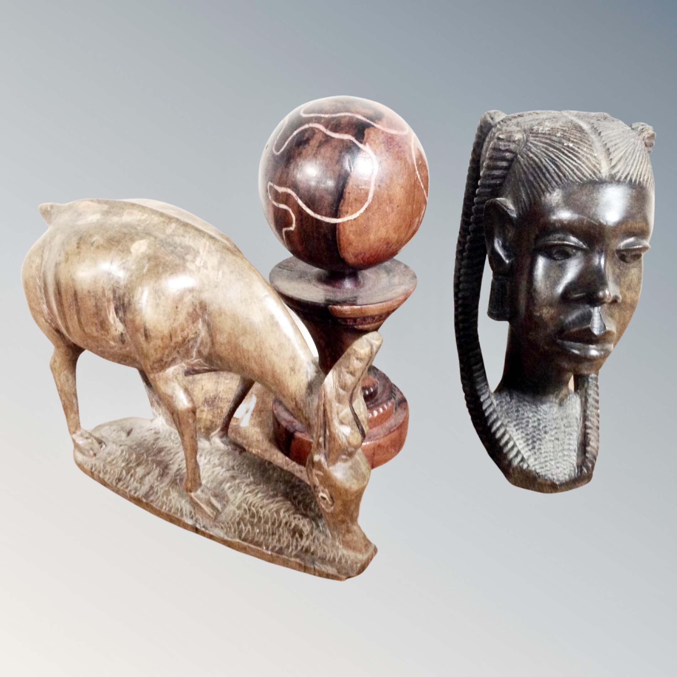 Three West African carved wooden figures depicting an antelope and female bust, tallest 22 cm.